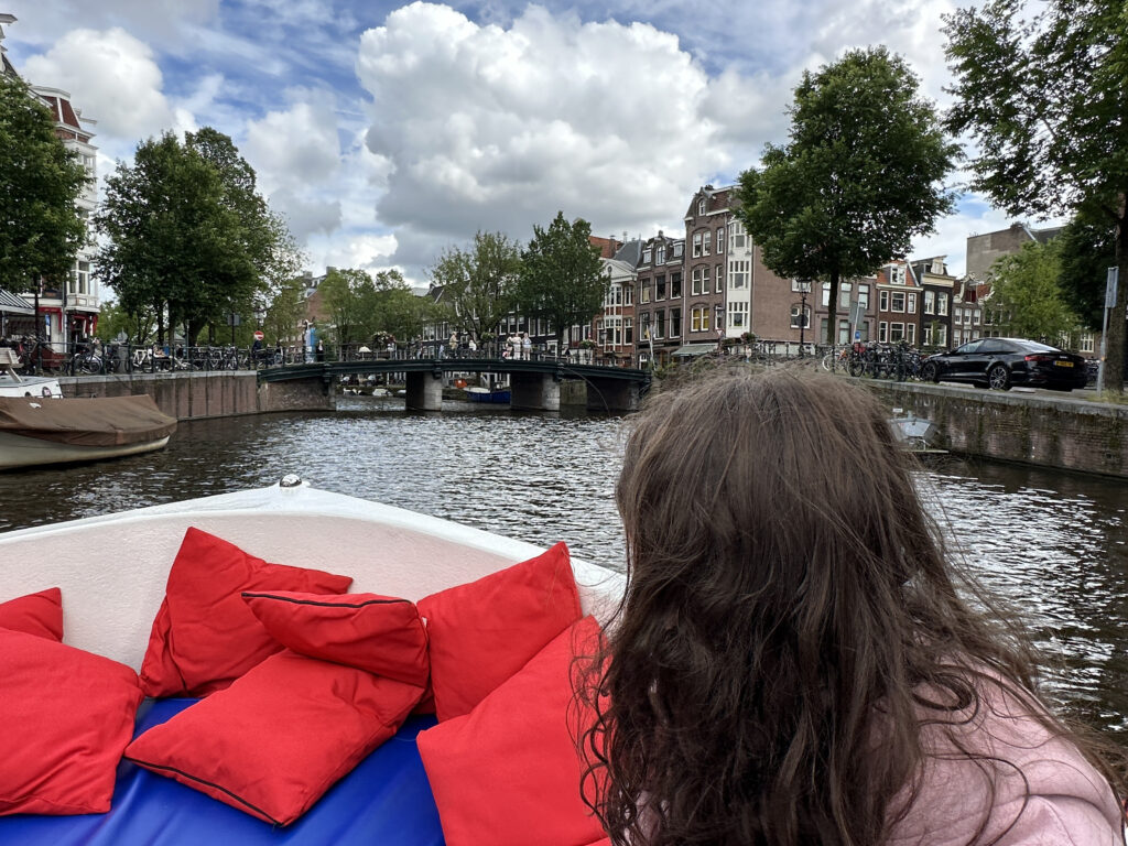 a woman sitting on a boat with red pillows on it