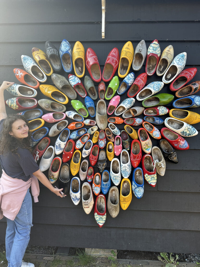 a woman standing next to a wall of shoes