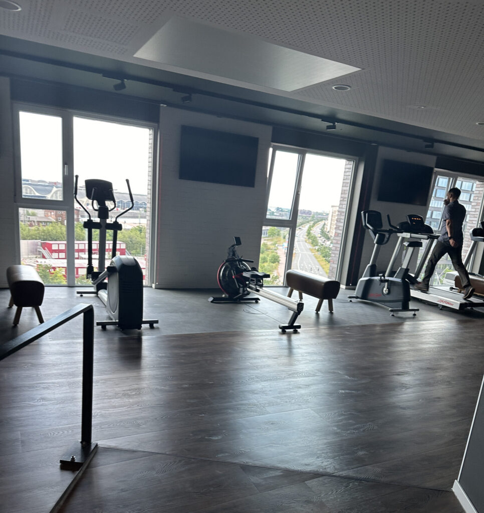 a room with exercise equipment and a person walking