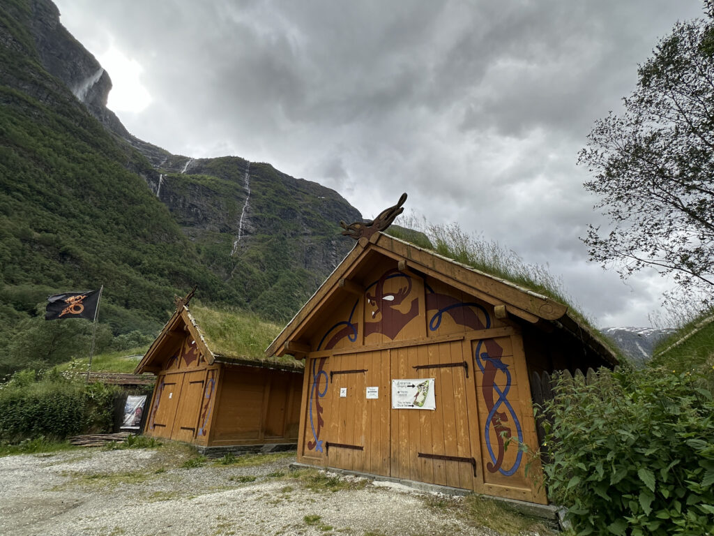 a two wooden buildings with grass on the roof