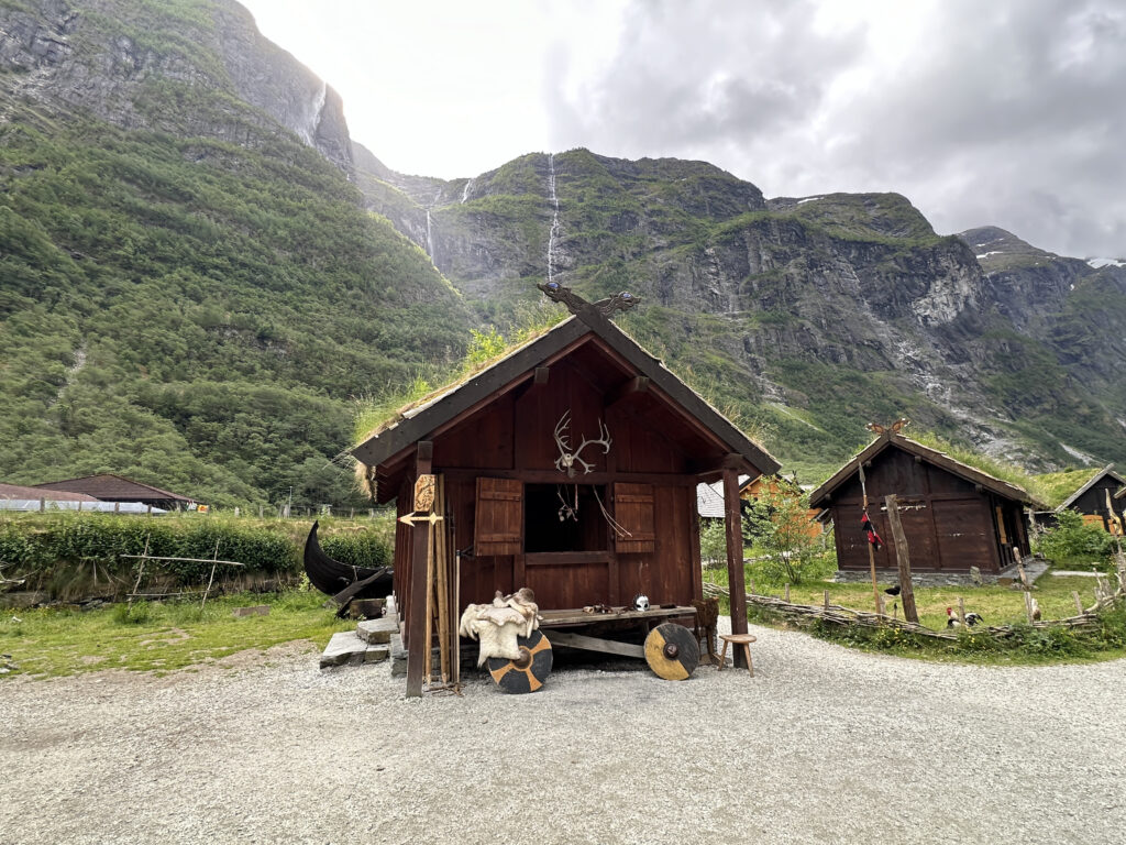 a small wooden house with grass roof and a mountain in the background