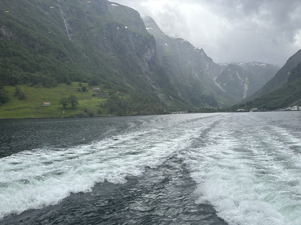 a boat wake in the water with mountains in the background