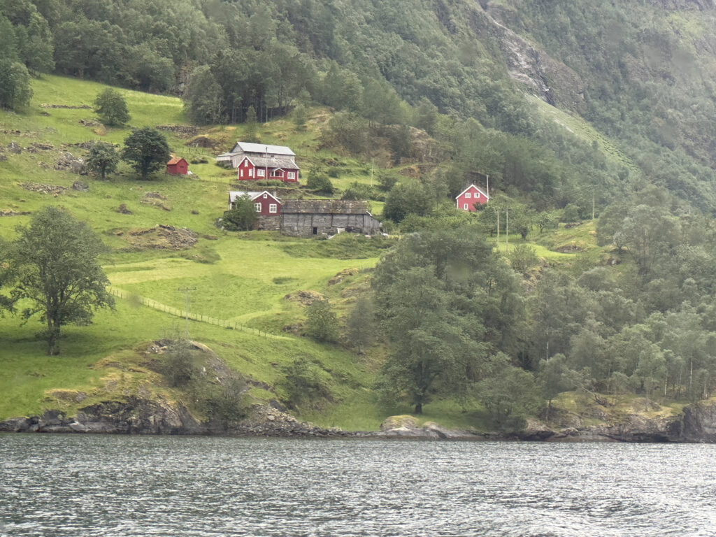 a red houses on a hill by a body of water
