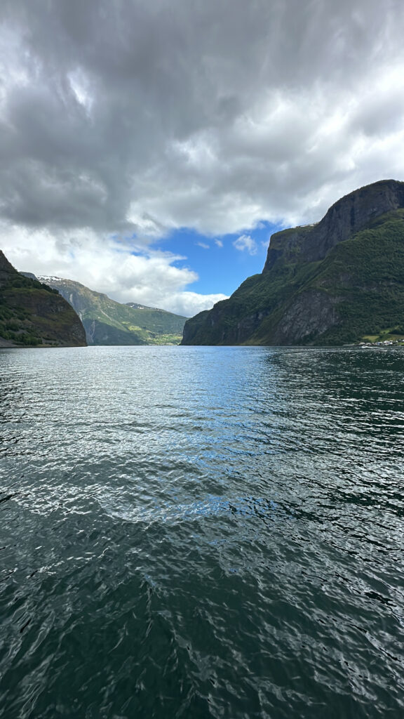 a body of water with mountains and clouds with Loch Ness in the background