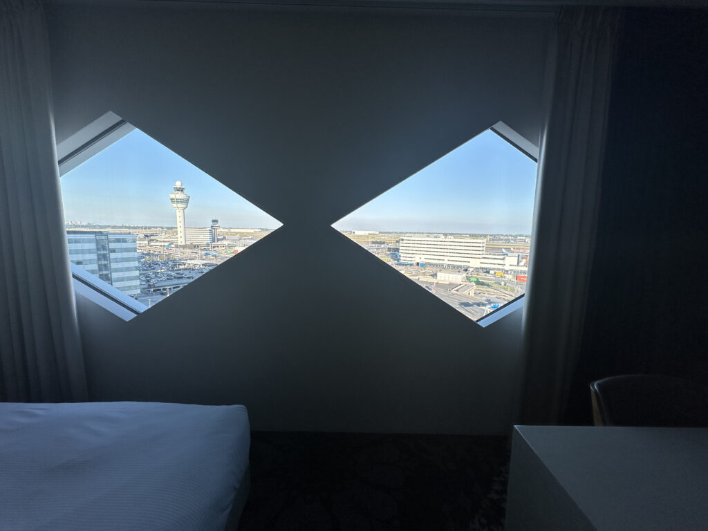 a room with a bed and a window with a view of the city