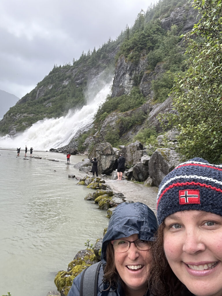 a selfie of two women in front of a waterfall