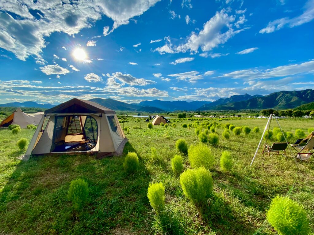 a tent in a field with mountains in the background