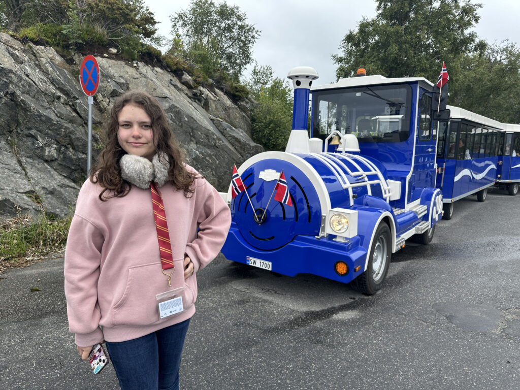 a girl standing in front of a blue train