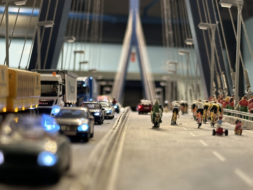 a group of people riding bicycles and cars on a bridge
