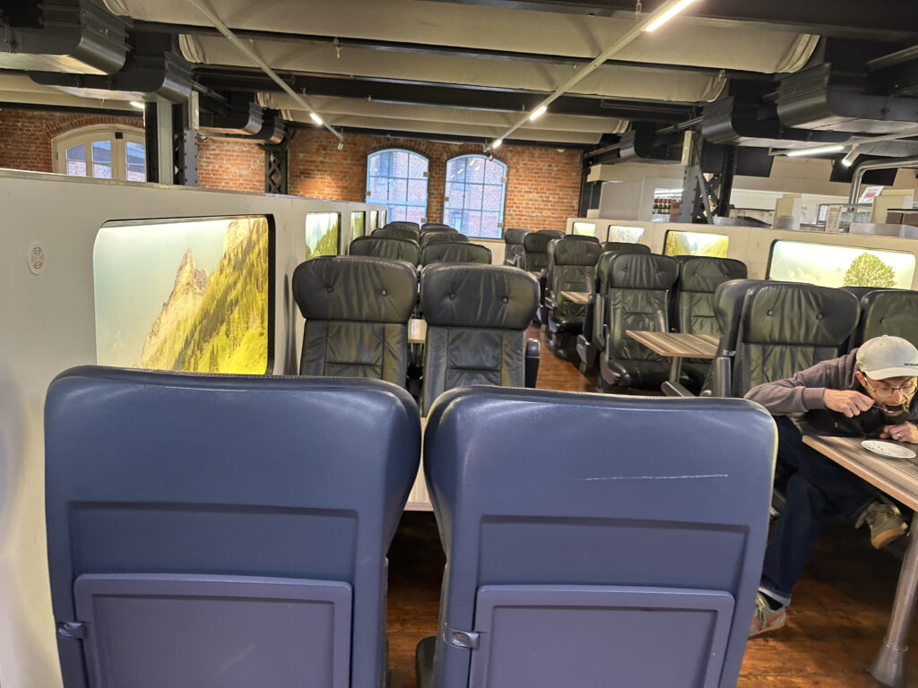 a man sitting in a room with chairs and televisions