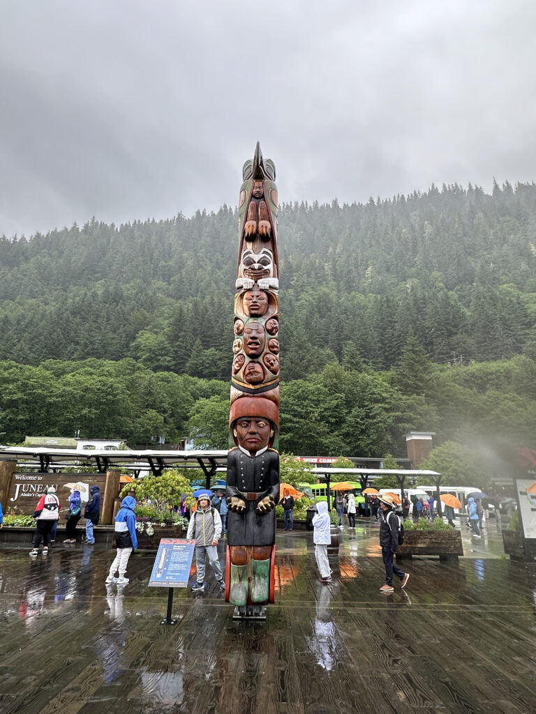 a large totem pole with people walking around