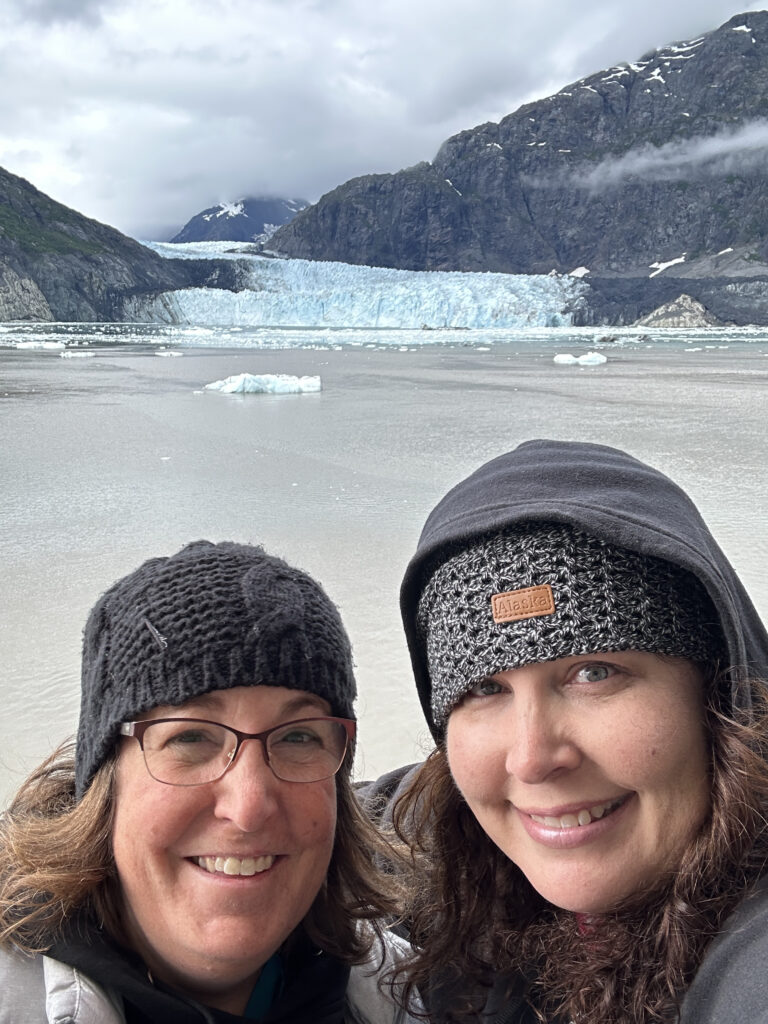 two women taking a selfie in front of a glacier