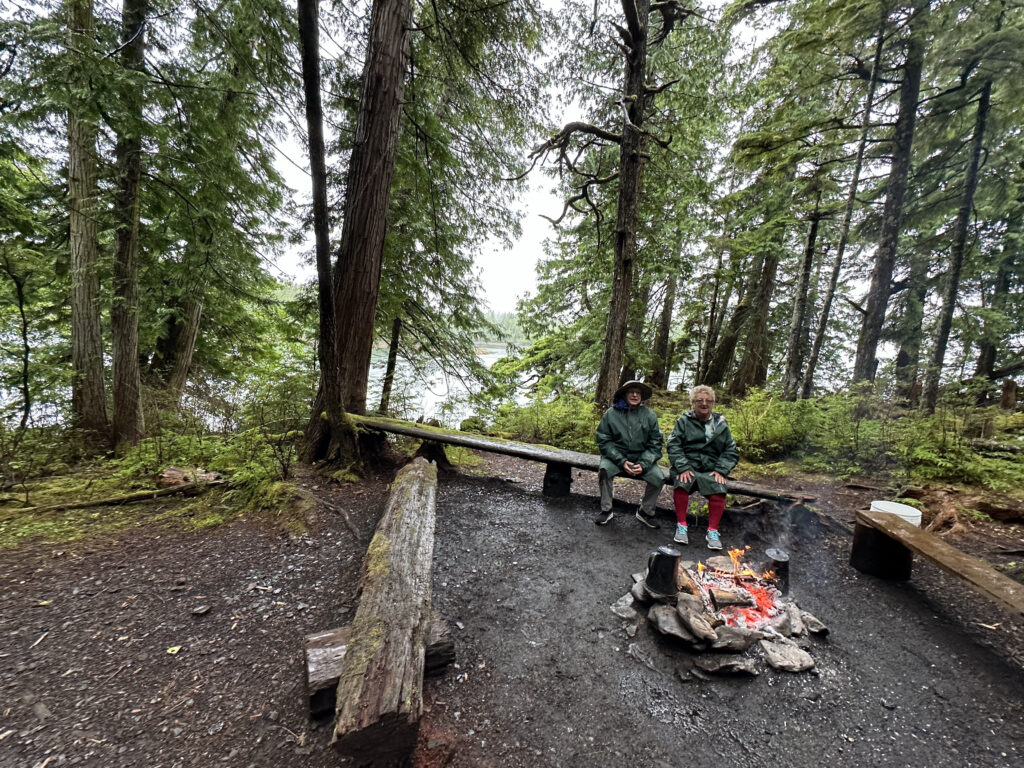 two people sitting on a bench near a fire