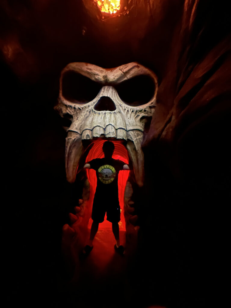 a person standing in a cave with a skull