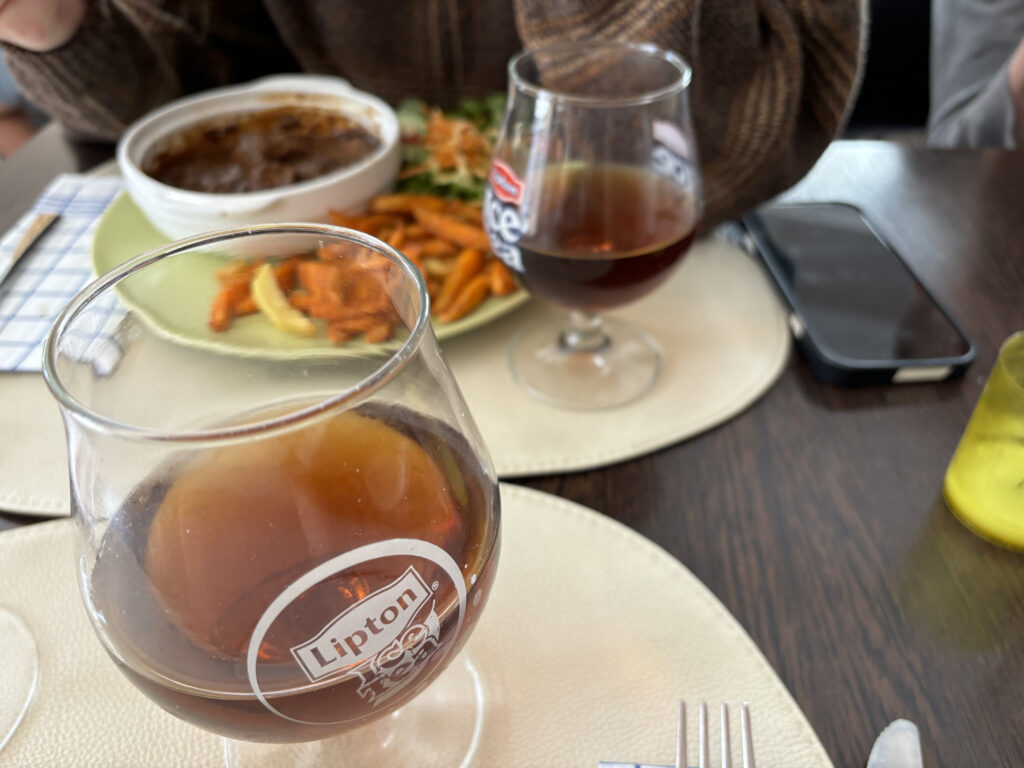 a glass of brown liquid next to a plate of food