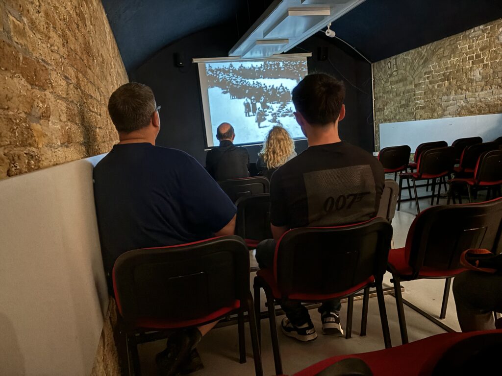a group of people sitting in chairs looking at a screen