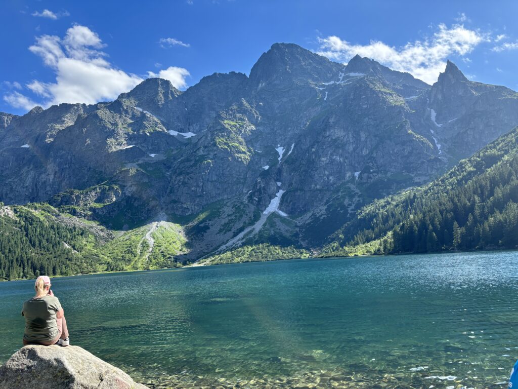 a person sitting on a rock by a lake