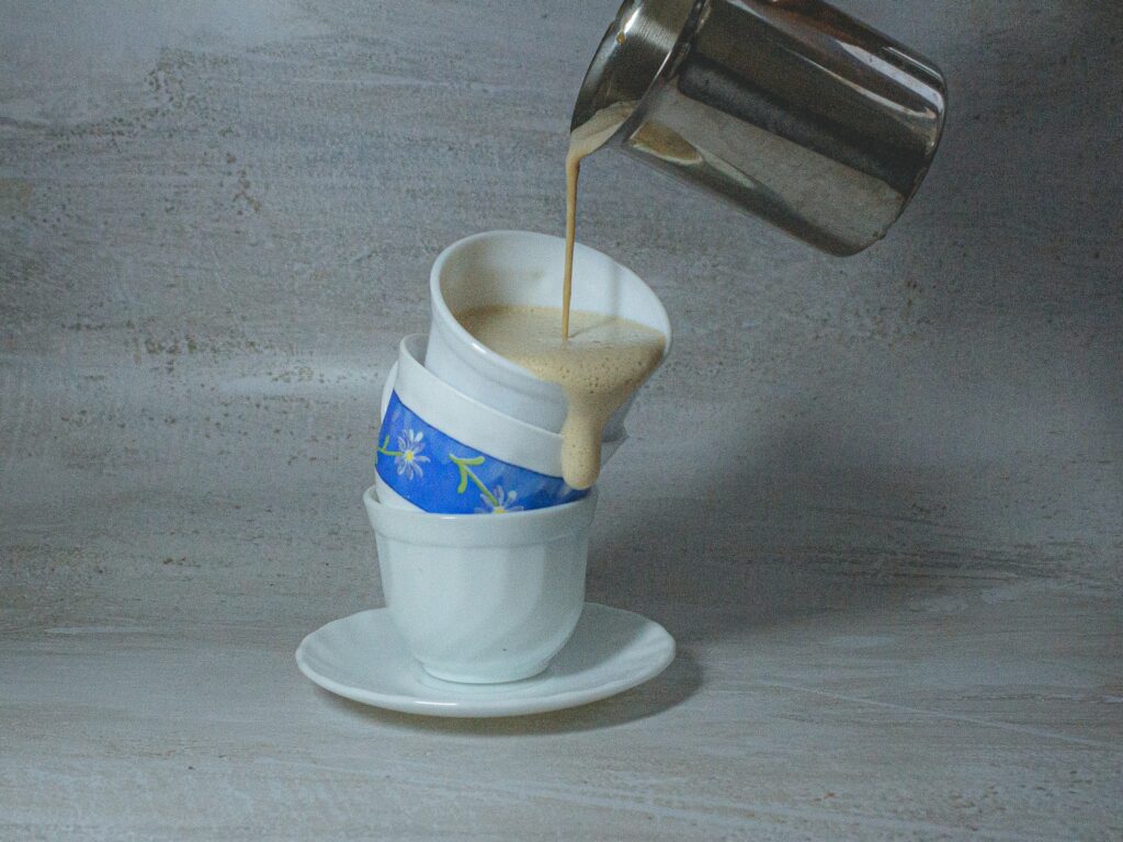 a coffee being poured into a stack of cups