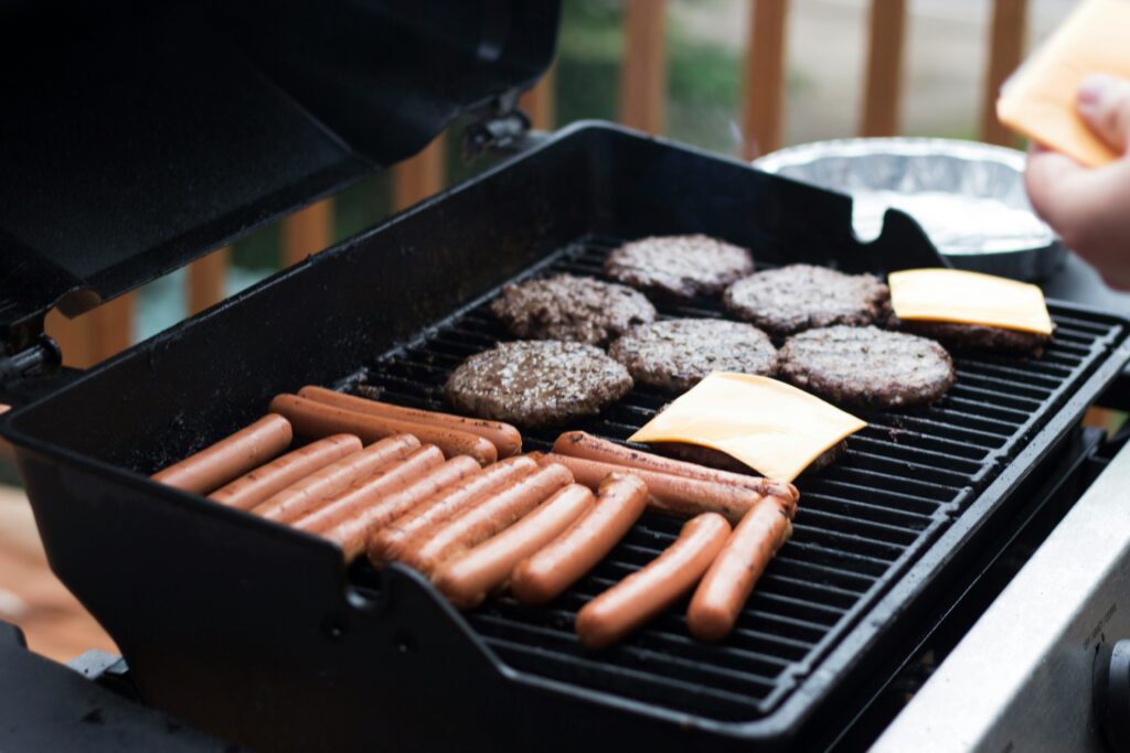 a grill with hamburgers and hot dogs
