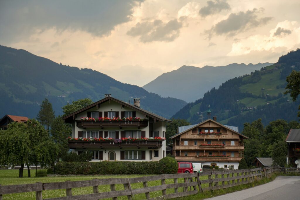 a two houses with trees and mountains in the background
