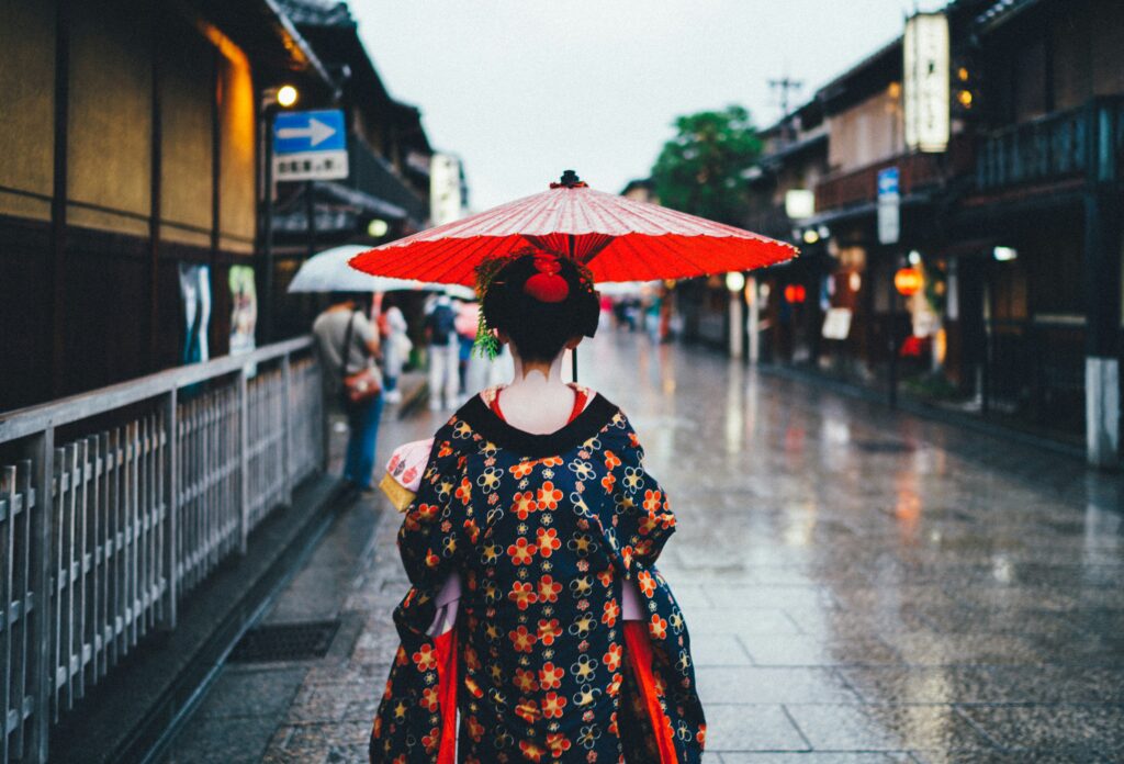 a woman in a kimono holding a red umbrella