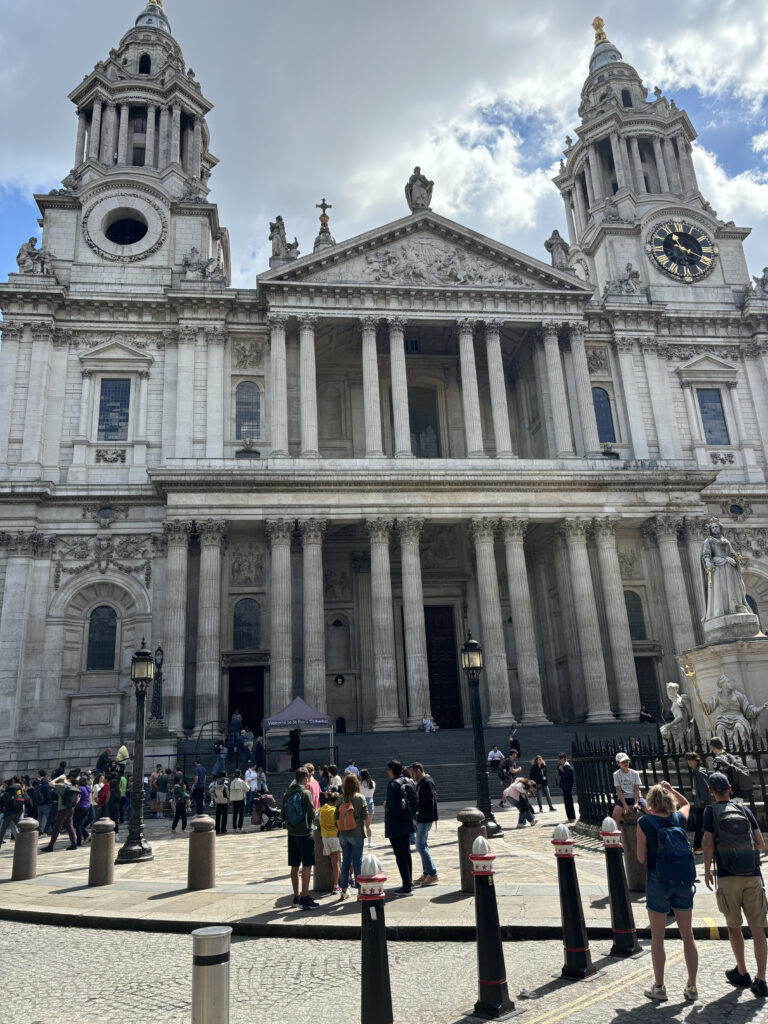 a group of people standing in front of a large white building with St Paul's Cathedral in the background