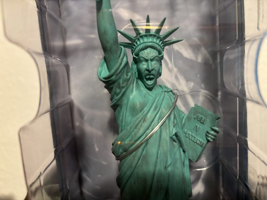 a statue of liberty in a plastic case with Statue of Liberty in the background