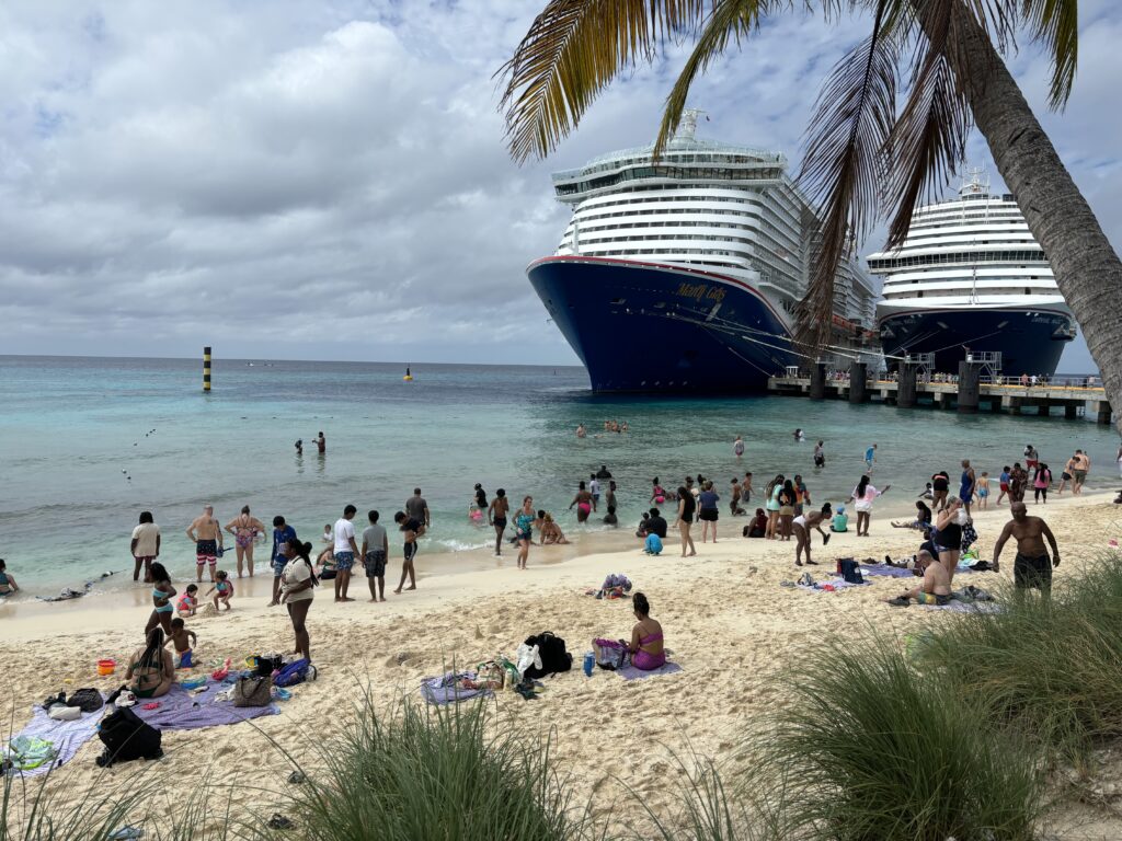 a group of people on a beach with a cruise ship in the background