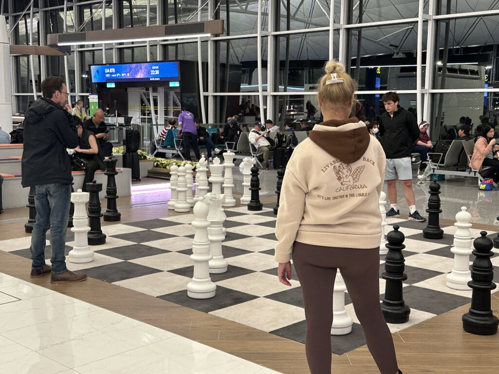 a woman standing in front of a large chess board