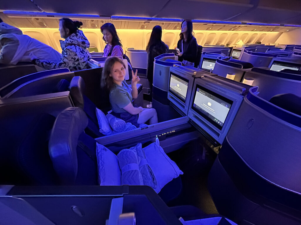 a woman sitting in an airplane with a peace sign