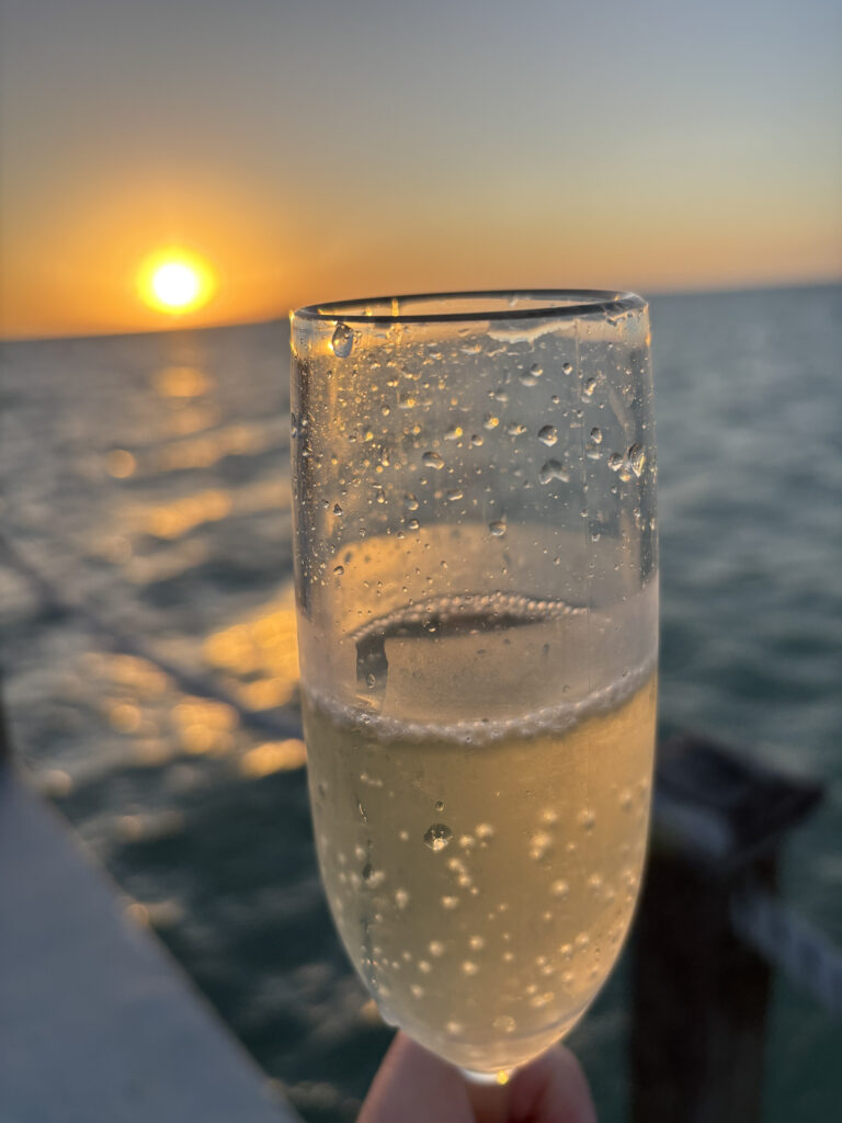 a glass of champagne with a sunset in the background