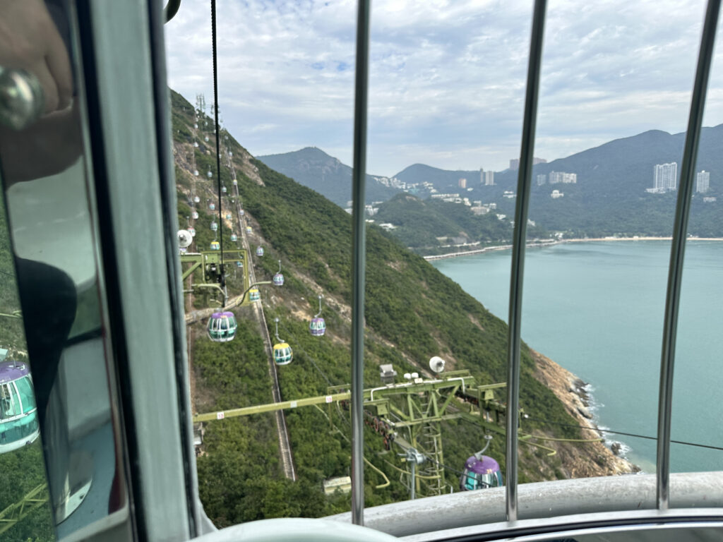 a cable car going up a hill with trees and water
