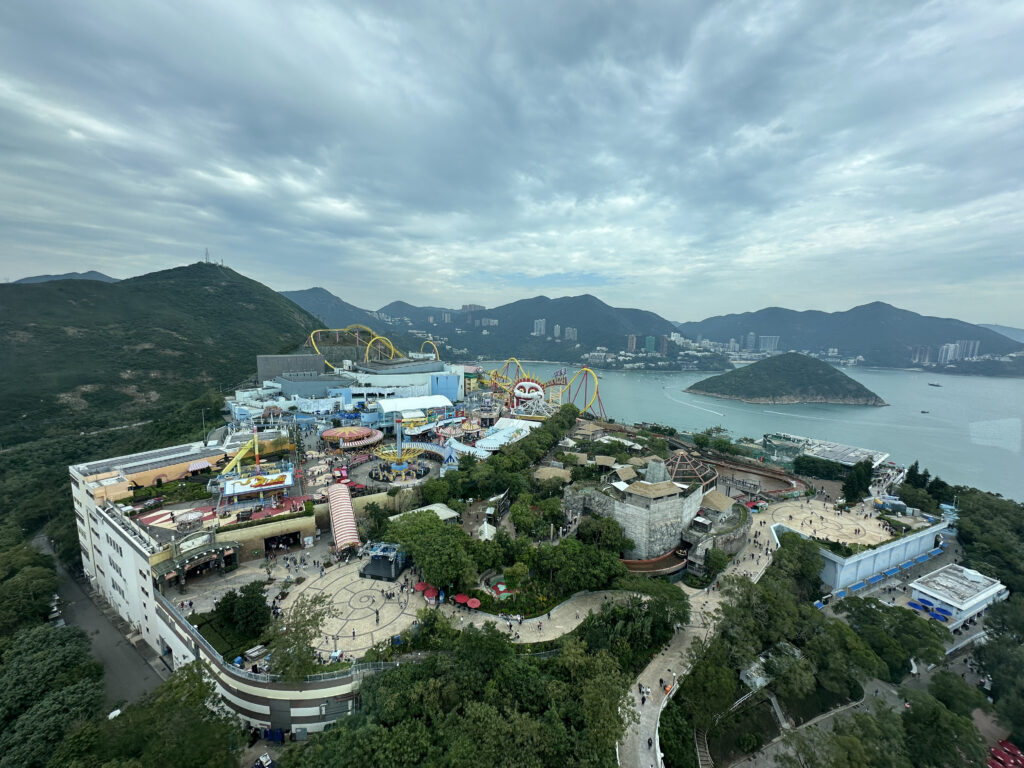 an amusement park with a body of water and mountains in the background