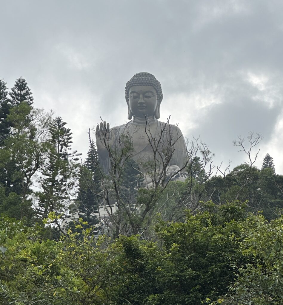 a large statue of a buddha surrounded by trees
