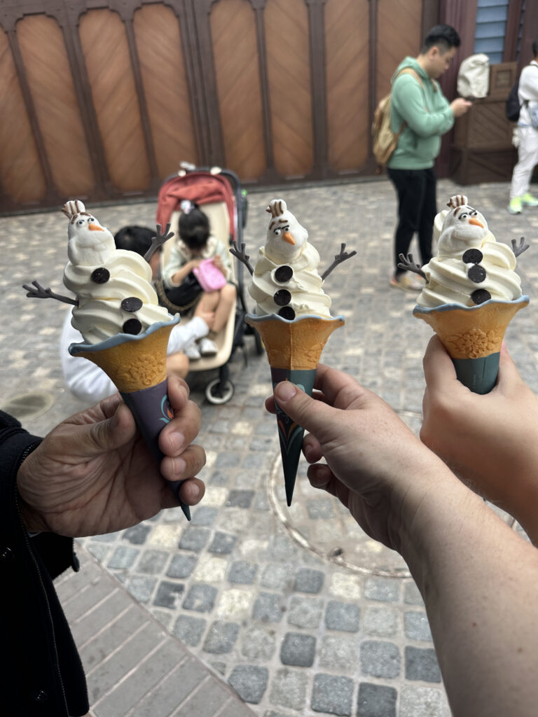a group of hands holding ice cream cones with snowman shaped ice cream