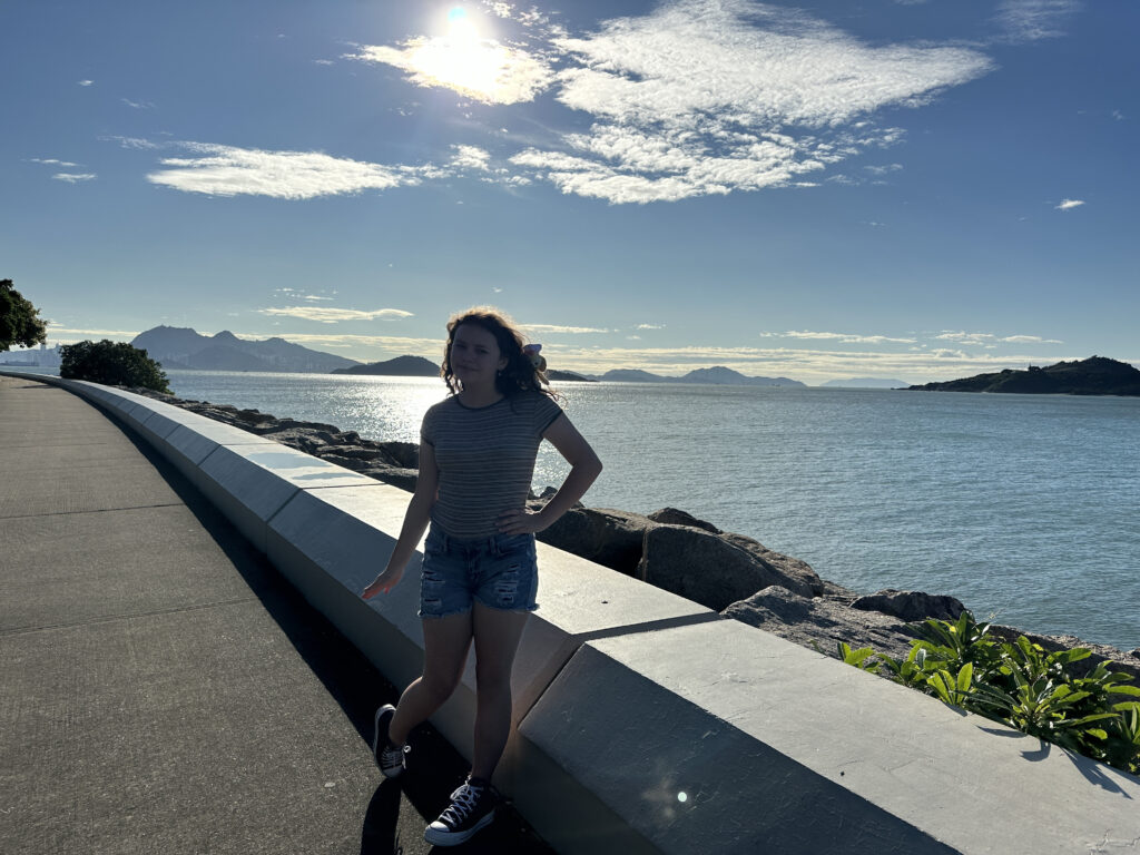 a woman standing on a road next to a body of water
