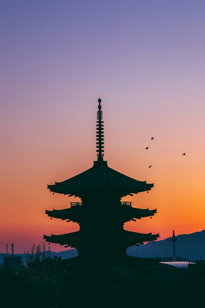 a silhouette of a pagoda with birds flying in the sky