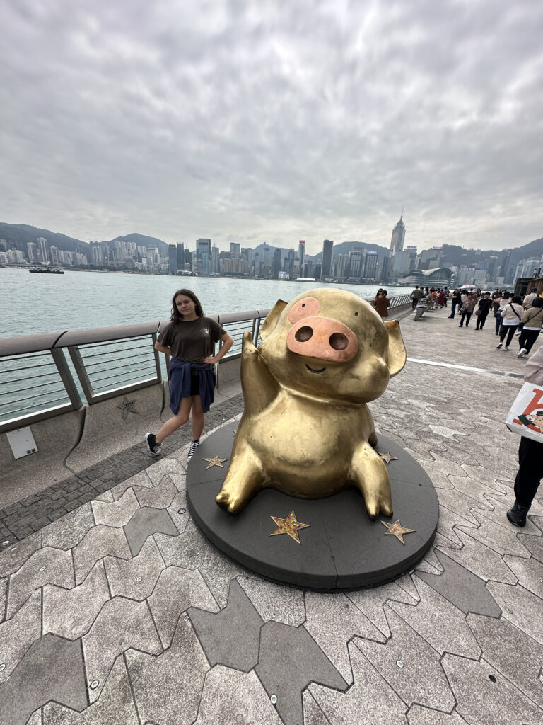a woman standing next to a statue of a pig
