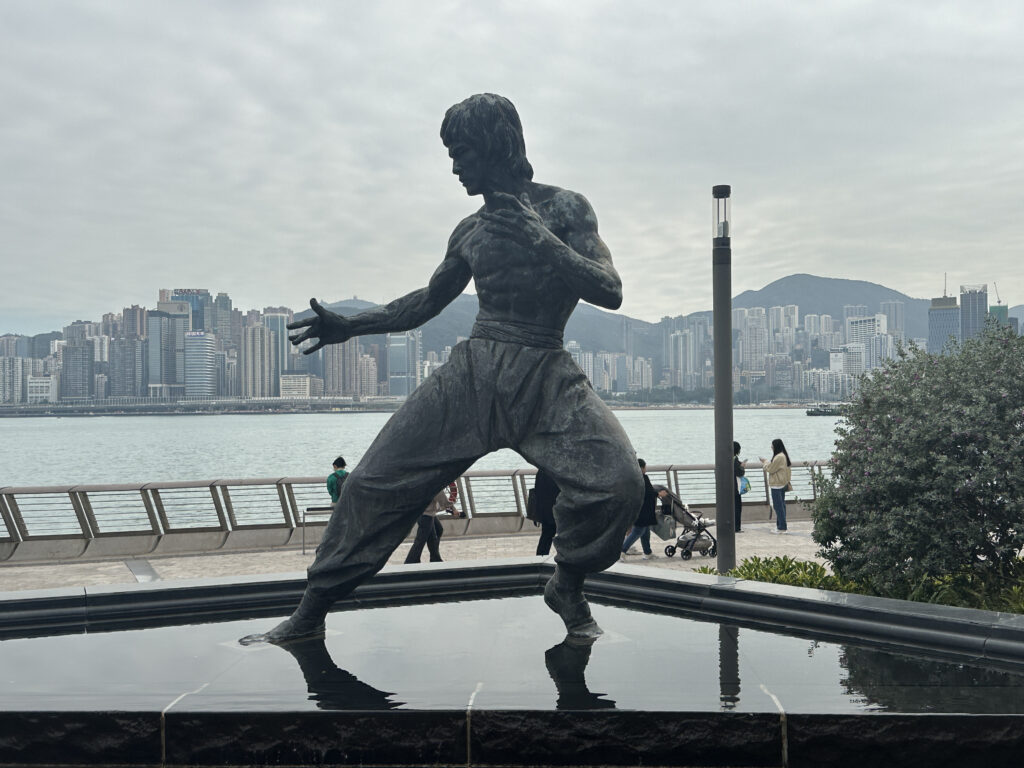 a statue of a man in a body of water with a city in the background