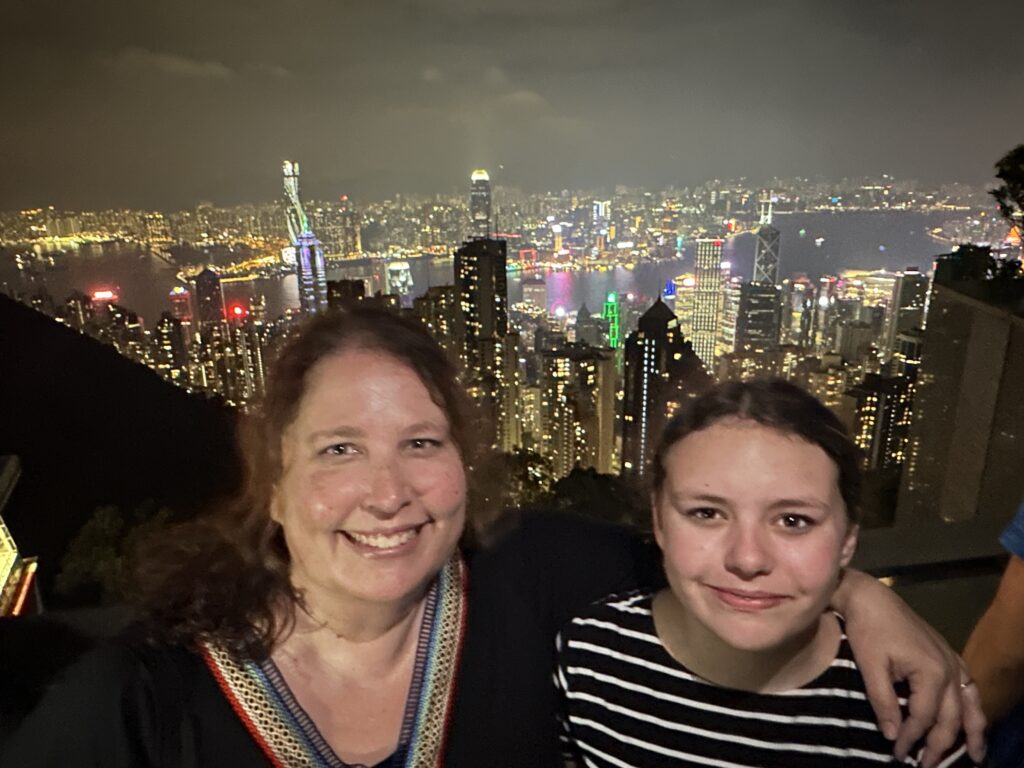 two women taking a selfie with a city in the background