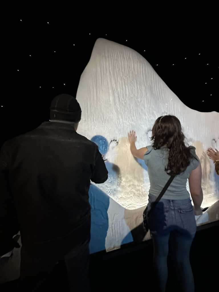 a group of people touching a large white and blue wall