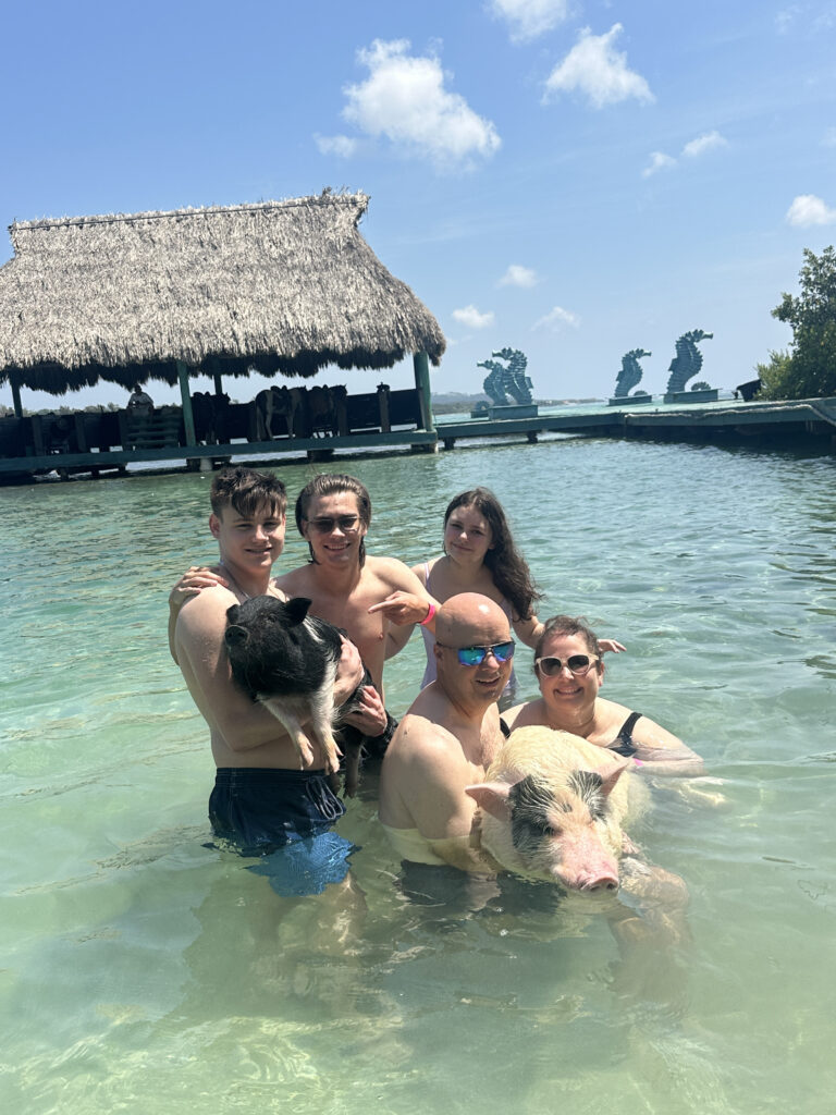 a group of people in the water with a pig in their arms