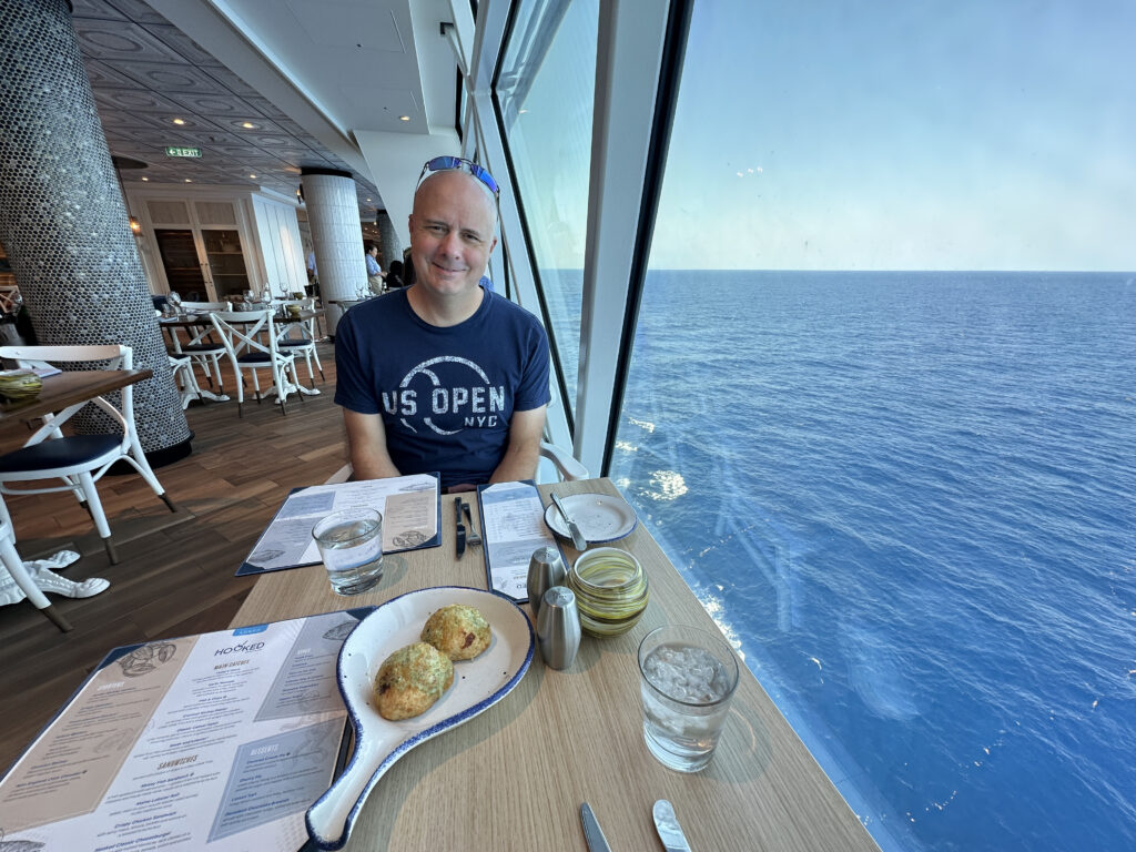 a man sitting at a table with a large window overlooking the ocean