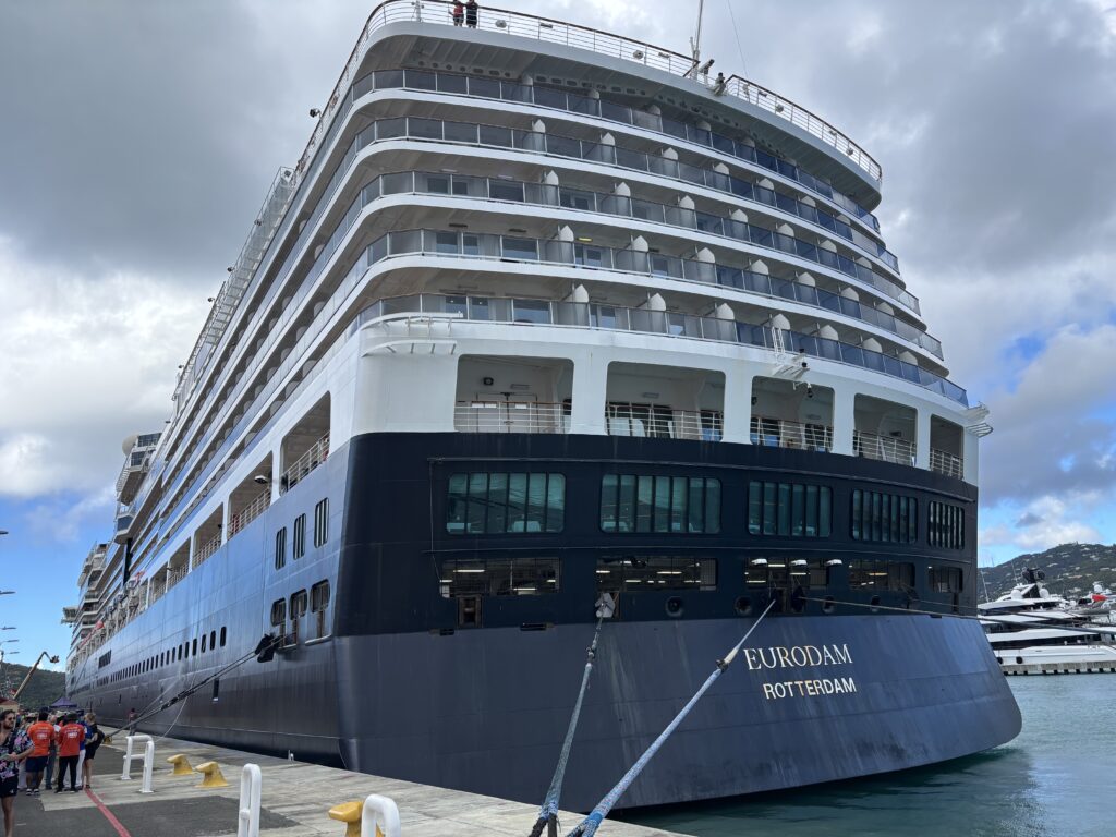 a large cruise ship docked at a dock with Reichstag dome in the background