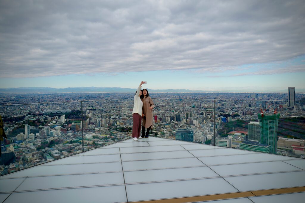 two people standing on a rooftop with a city in the background