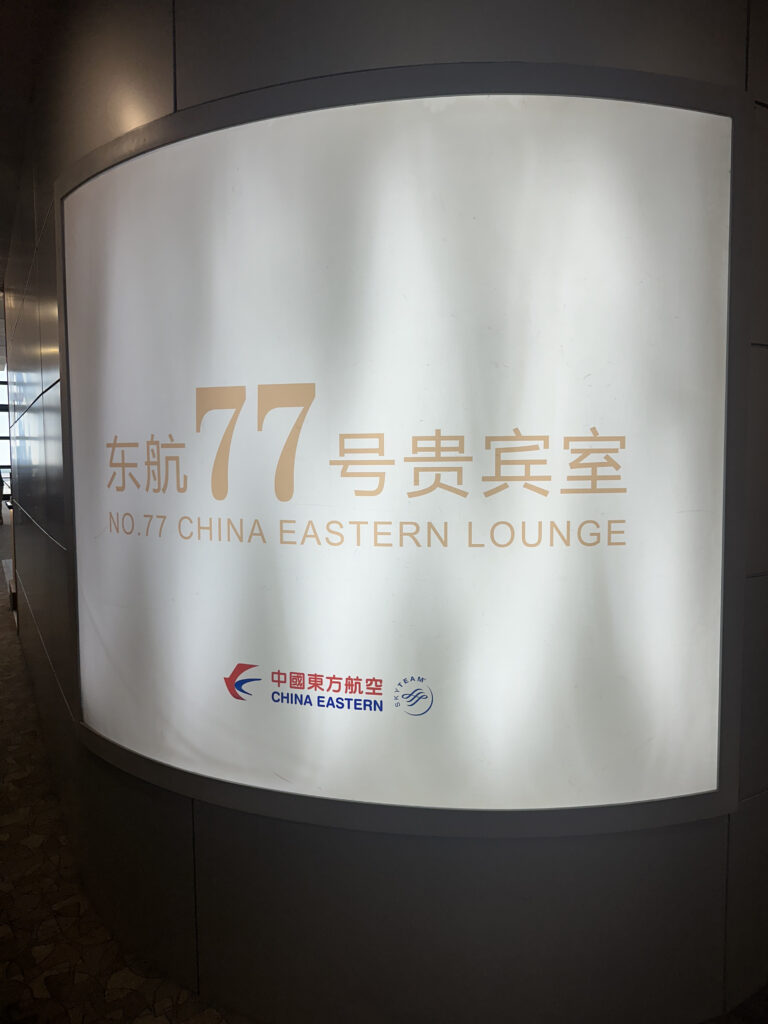 The image shows a sign for the "No. 77 China Eastern Lounge." The sign includes text in both Chinese and English, and features the China Eastern Airlines logo along with the SkyTeam logo. The background is a light color, and the text is prominently displayed.