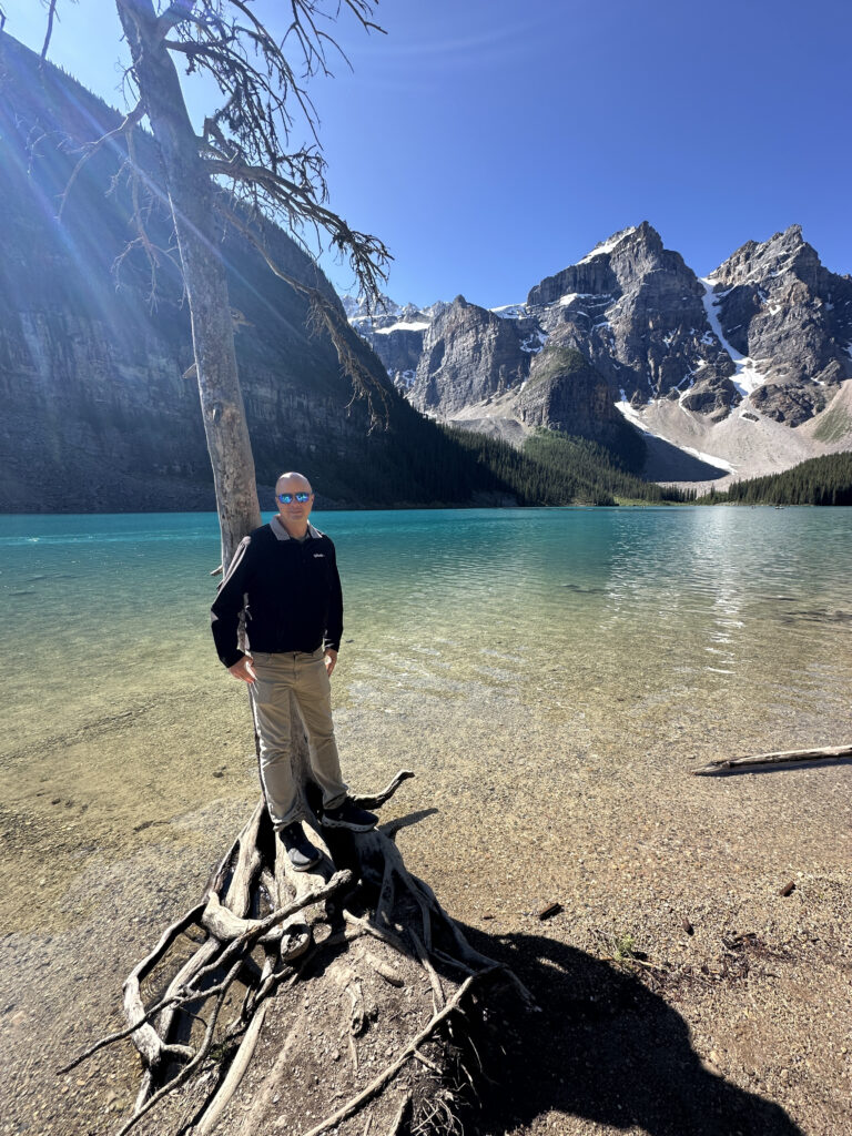 a man standing next to a tree by a lake