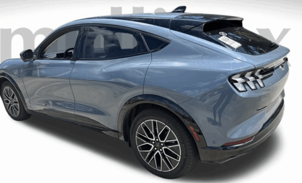 The image shows a blue SUV with a sleek design, viewed from the rear side. The vehicle has tinted windows and distinctive taillights. It is displayed on a plain background with a website URL at the bottom.